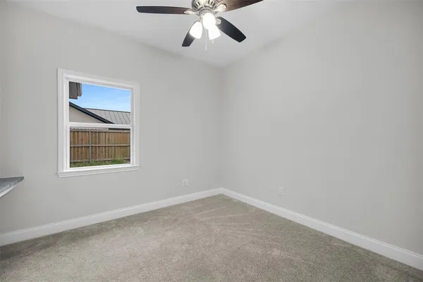 an empty room with a window and a fan