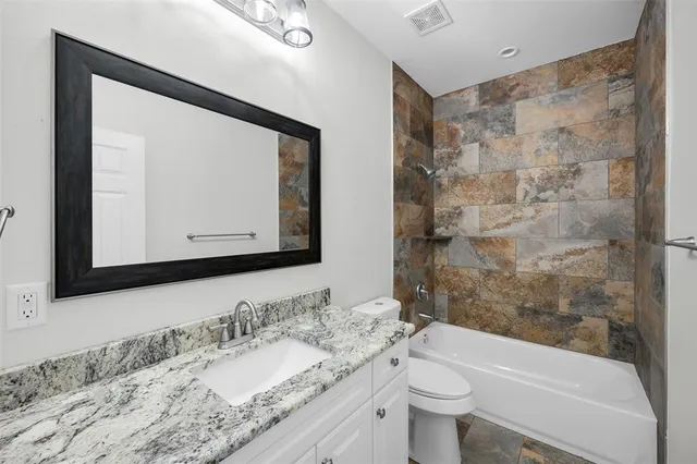 a bathroom with a granite countertop sink a toilet and a mirror