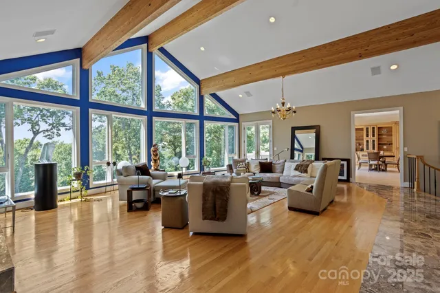 a living room with furniture large windows and wooden floor