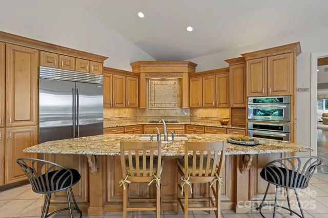 a kitchen with stainless steel appliances kitchen island granite countertop a table chairs and a refrigerator