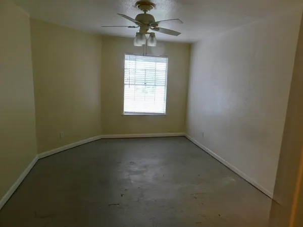 an empty room with a window and a fan