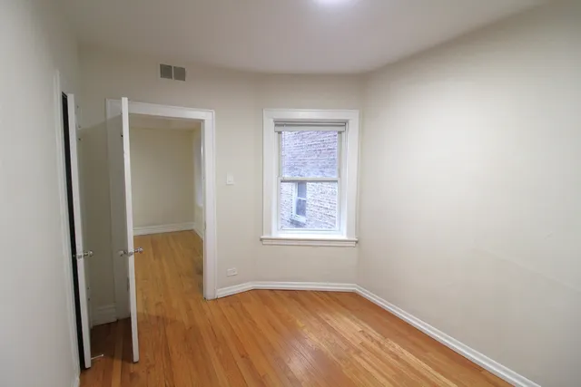 a view of an empty room with wooden floor and closet
