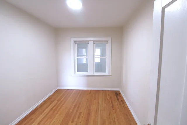 an empty room with wooden floor and a window