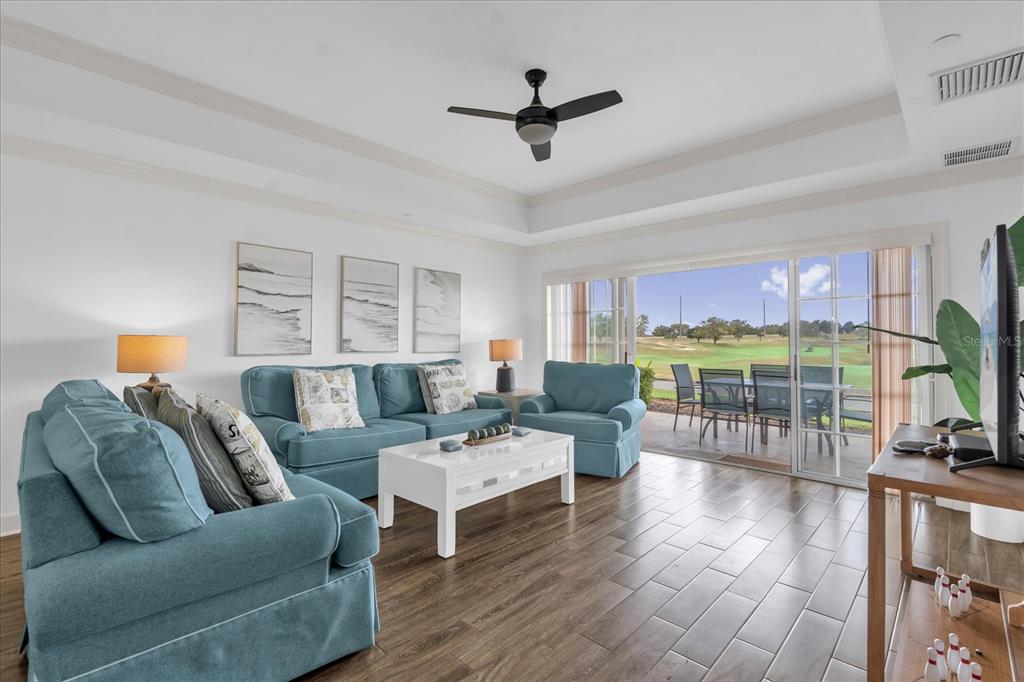 1362 Centre Ct Ridge Drive, Unit 102 Reunion, FL 34747 - Photo 6 of 35 a living room with furniture a lamp wooden floor and a floor to ceiling window