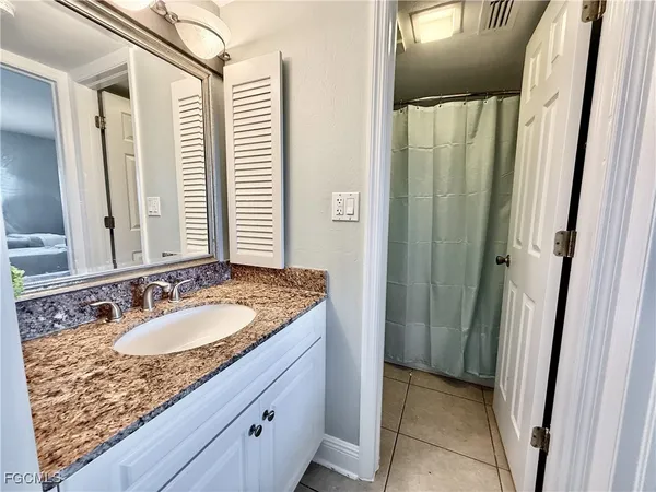 a bathroom with a granite countertop sink and a mirror