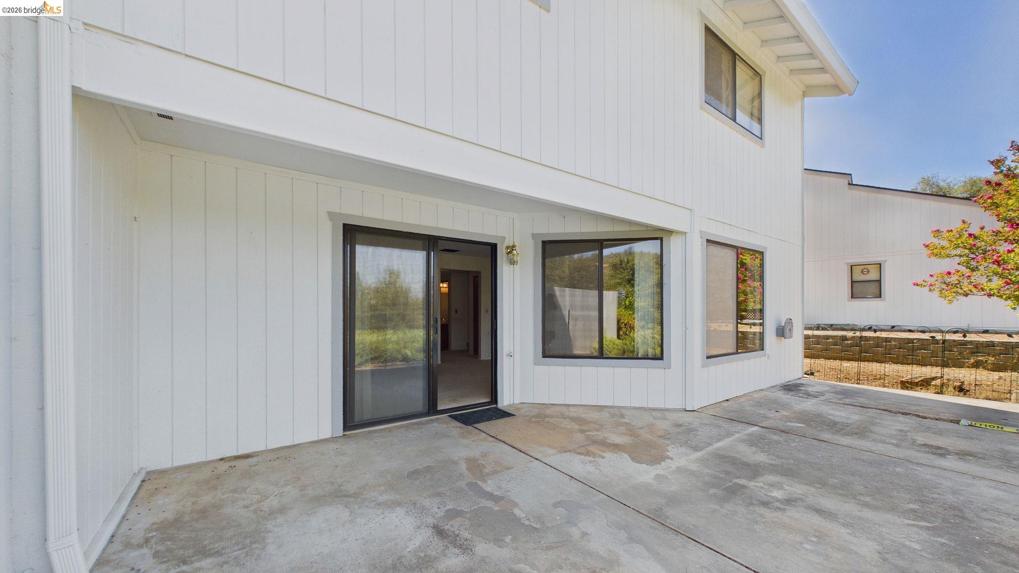 23686 Marble Quarry Road, Unit 72 Columbia, CA 95310 - Photo 33 of 35 White vertical siding exterior, concrete patio, sliding glass door, and multiple windows