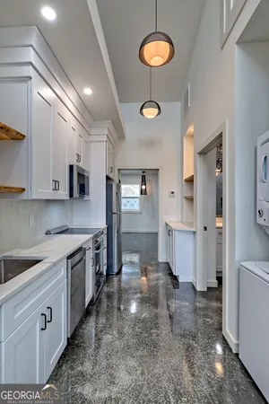 a large kitchen with stainless steel appliances a stove a sink a refrigerator and white cabinets with wooden floor