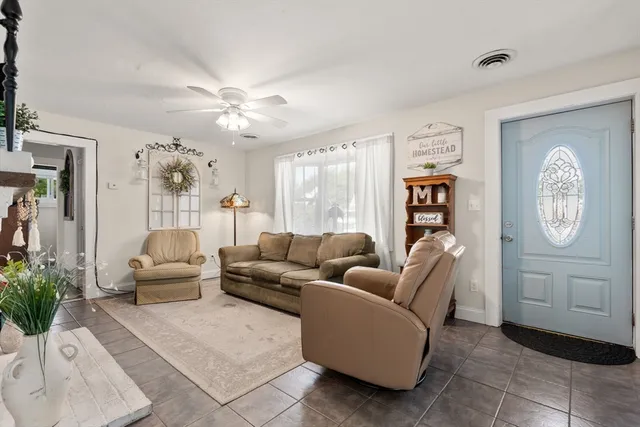 a living room with furniture a clock and a ceiling fan