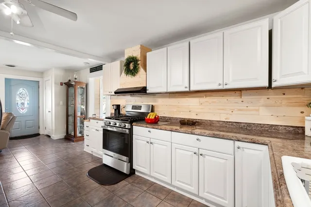 a kitchen with stainless steel appliances granite countertop a stove a sink and a white cabinets