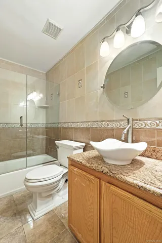 a bathroom with a granite countertop sink mirror vanity and toilet