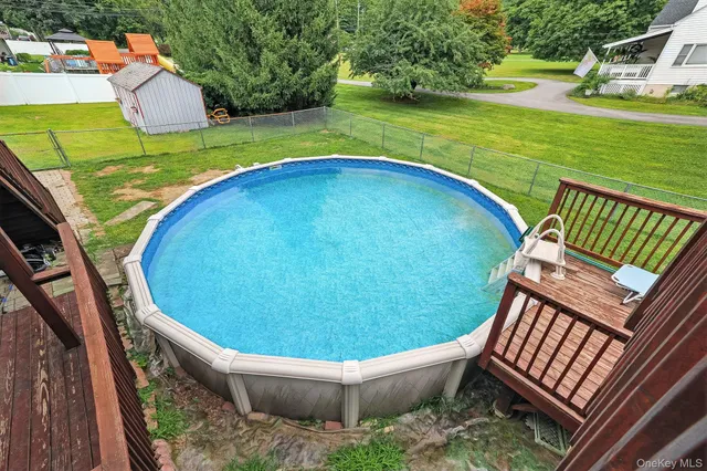 a view of a swimming pool with a patio and a yard