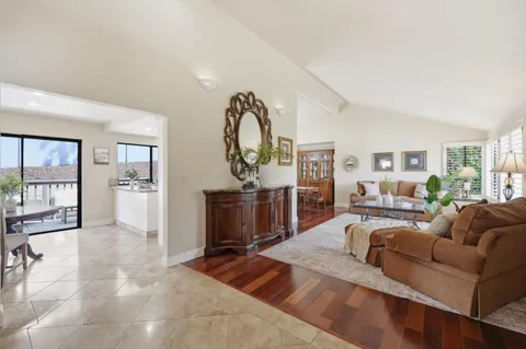 a living room with furniture a chandelier and a dining table with wooden floor