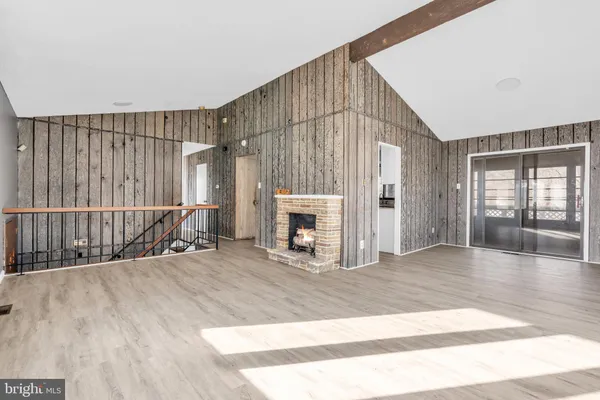 a view of an empty room with wooden floor and fireplace