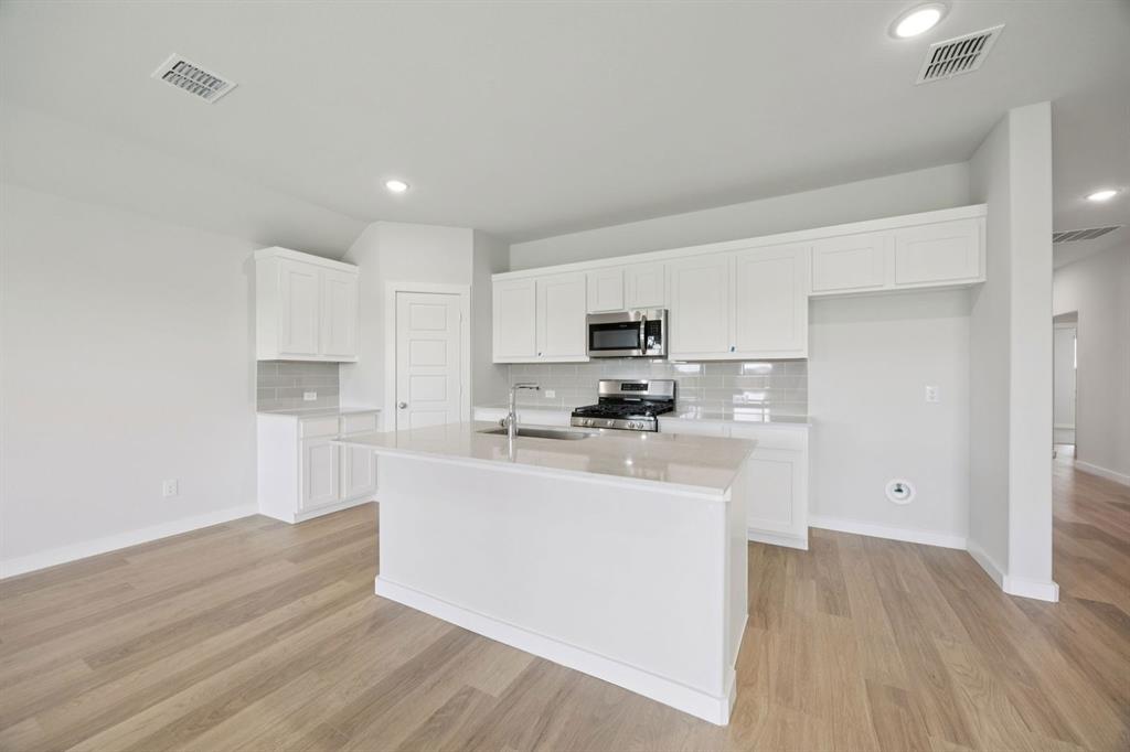 1868 Gallop Road Seagoville, TX 75159 - Photo 5 of 27 a kitchen with stainless steel appliances a sink a stove a refrigerator cabinets and a wooden floor