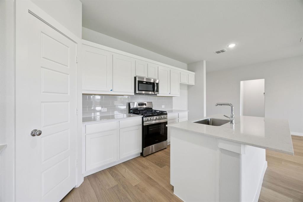1868 Gallop Road Seagoville, TX 75159 - Photo 7 of 27 a kitchen with stainless steel appliances granite countertop white cabinets a refrigerator a stove a sink and dishwasher with wooden floor