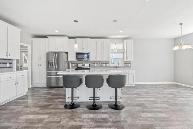 a kitchen with kitchen island granite countertop a refrigerator cabinets and chairs