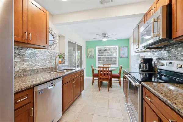 a kitchen with stainless steel appliances granite countertop a stove a refrigerator a kitchen island a table and chairs with wooden floor