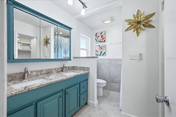 a bathroom with a granite countertop sink mirror and toilet