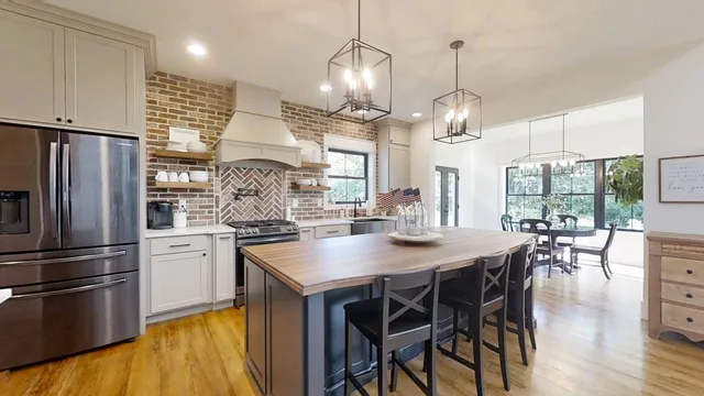 a kitchen with stainless steel appliances granite countertop a table chairs stove and refrigerator