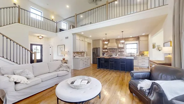 a living room with furniture kitchen view and a wooden floor