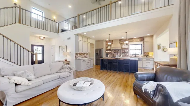 a living room with furniture kitchen view and a wooden floor