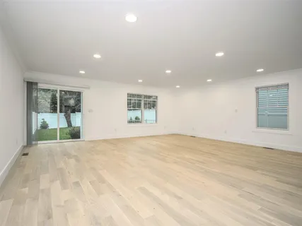 a large kitchen with stainless steel appliances granite countertop a stove a sink a refrigerator and white cabinets with wooden floor