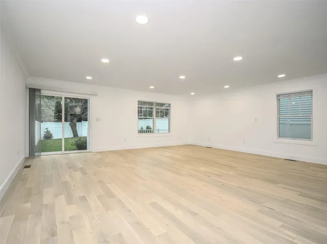 a large kitchen with stainless steel appliances granite countertop a stove a sink a refrigerator and white cabinets with wooden floor