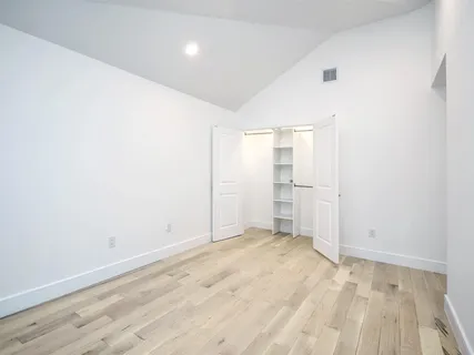 a view of an empty room with wooden floor and windows