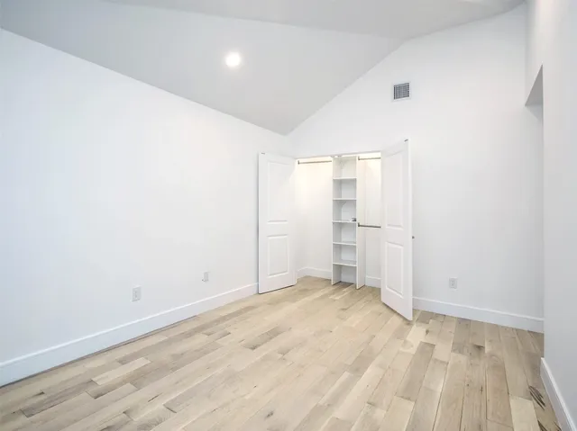 a view of an empty room with wooden floor and windows