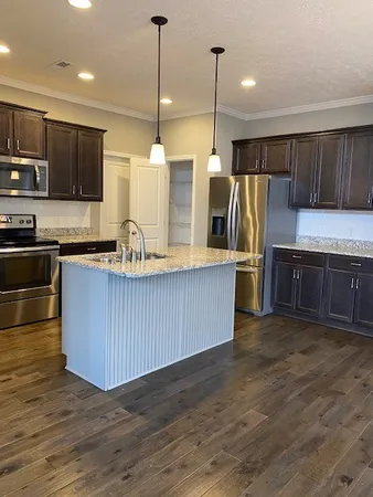 a kitchen with stainless steel appliances wooden floors wooden cabinets a refrigerator and a stove
