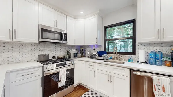 a kitchen with white cabinets appliances a sink and a window
