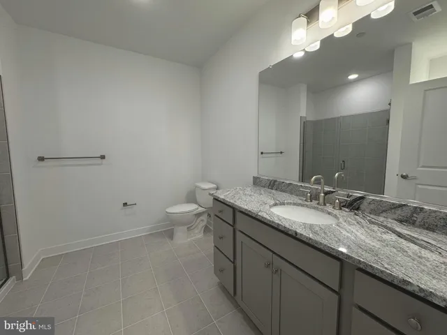 a bathroom with a granite countertop sink a toilet and a mirror