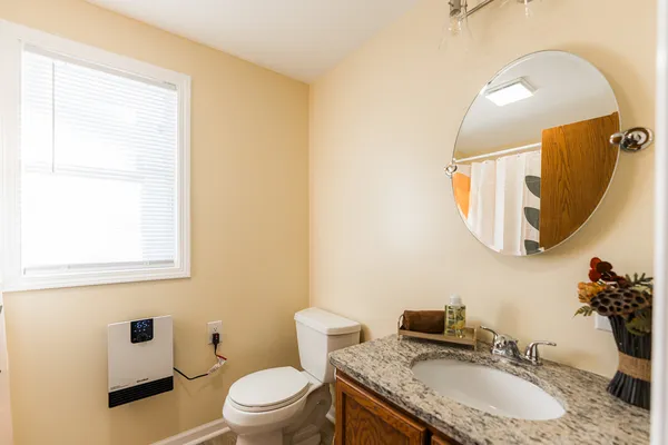 a bathroom with a granite countertop sink a mirror and a toilet
