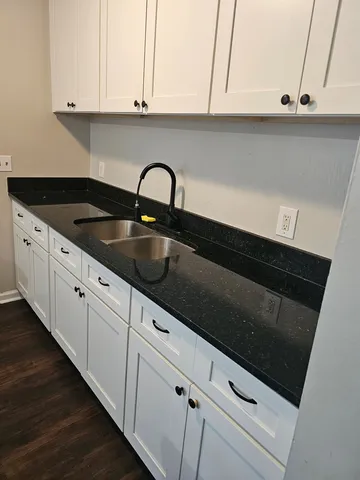 a kitchen with granite countertop white cabinets and sink