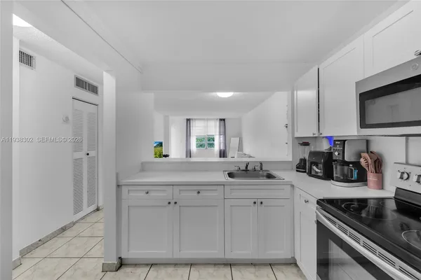 a kitchen with white cabinets and appliances