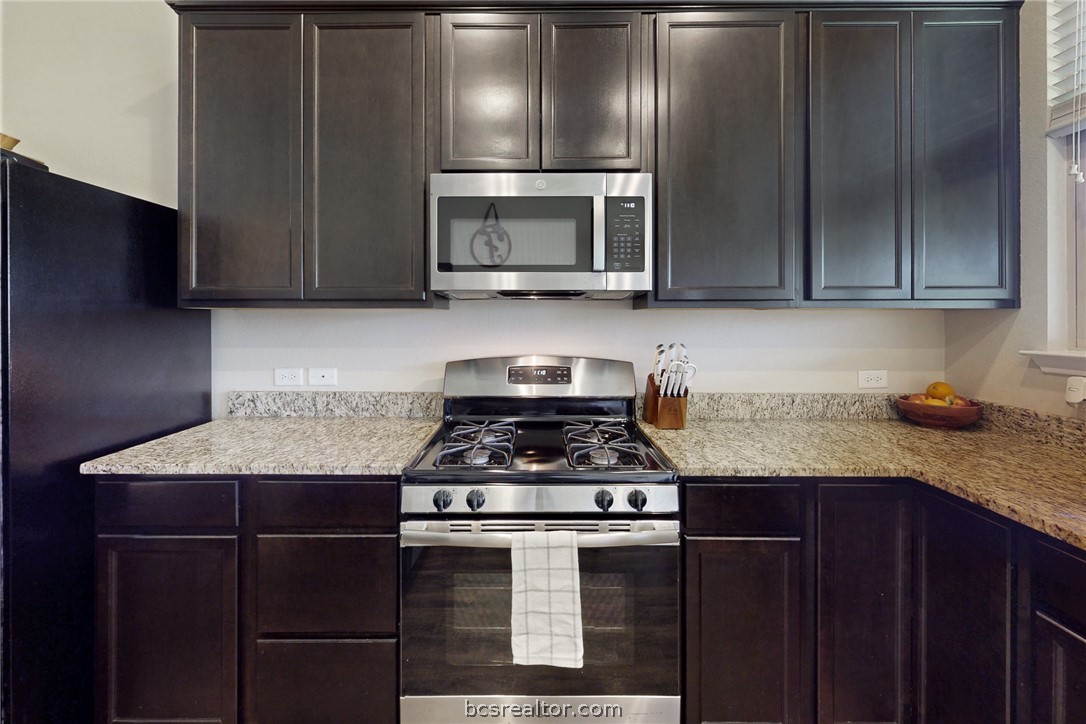 2071 Positano Loop Bryan, TX 77808 - Photo 11 of 31 a kitchen with granite countertop stainless steel appliances and wooden cabinets