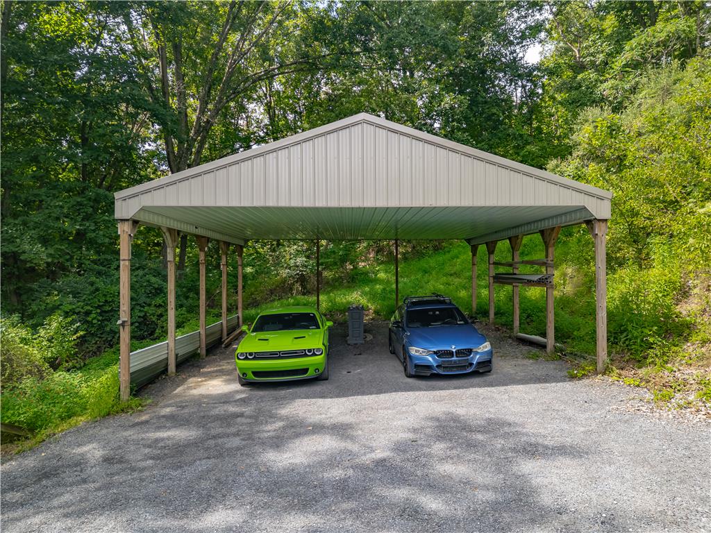 7353 Farrier Road Orefield, PA 18069 - Photo 56 of 74 A spacious metal carport provides sheltered outdoor parking nestled against a dense wooded backdrop.