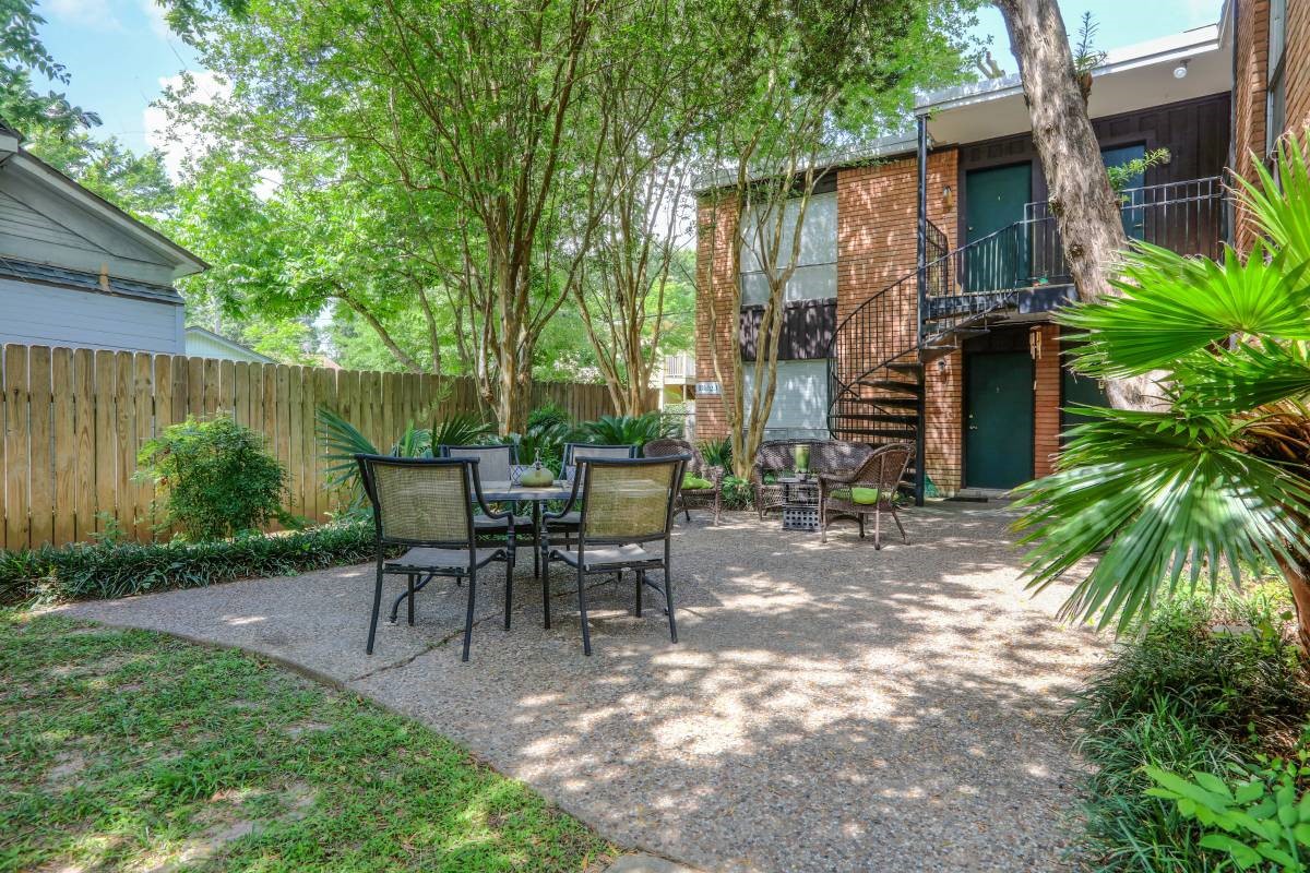 a view of a patio with table and chairs potted plants and large tree