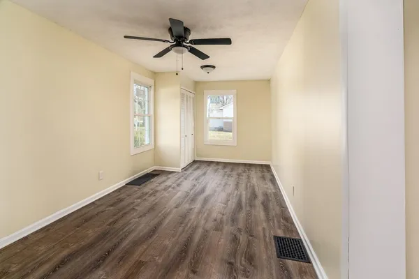 an empty room with wooden floor and ceiling fan