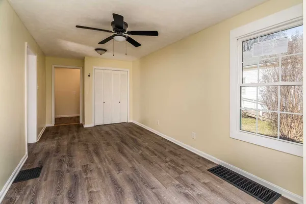 a view of empty room with wooden floor and fan