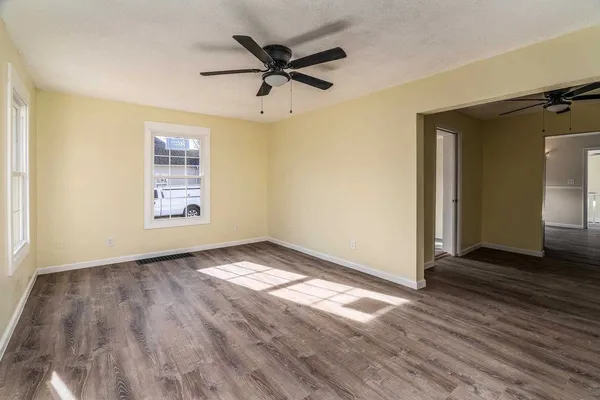 a view of empty room with wooden floor and fan