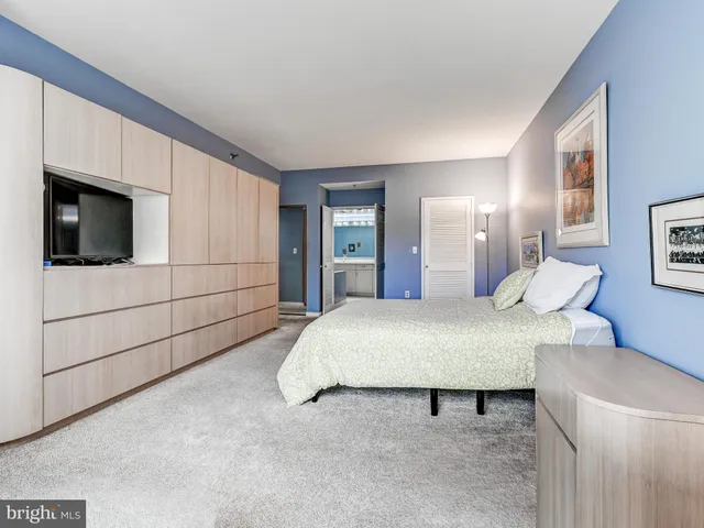 a spacious bedroom with a bed and a view of cabinet