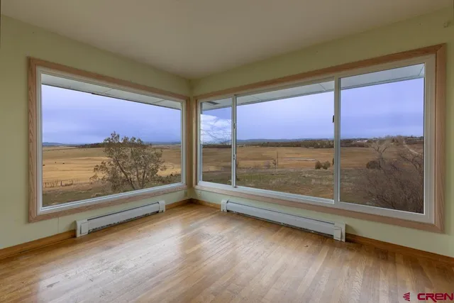 a view of an empty room with window and wooden floor