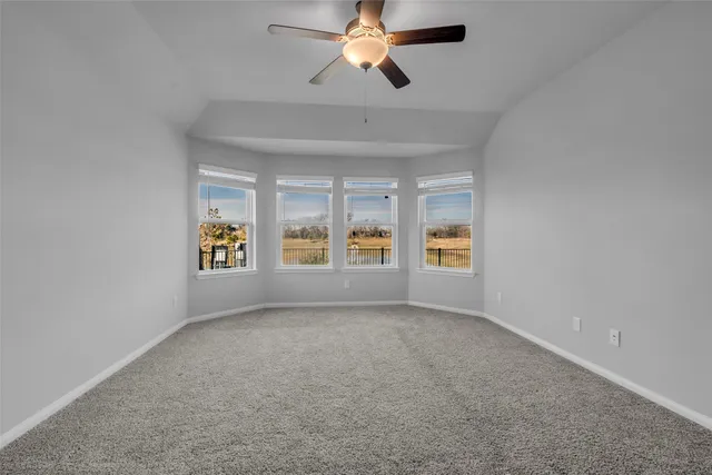 an empty room with chandelier fan and windows