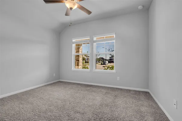 an empty room with windows and chandelier fan