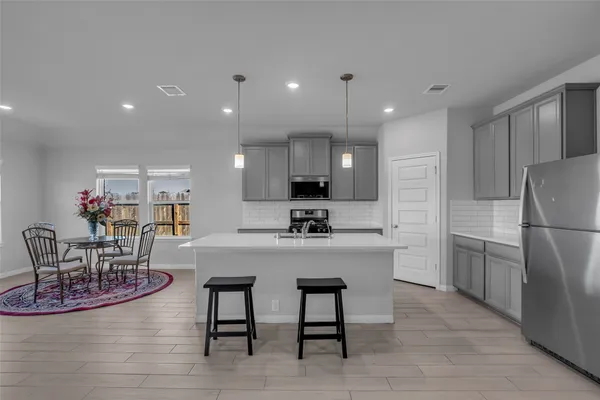 a kitchen with stainless steel appliances granite countertop a table chairs refrigerator and a sink