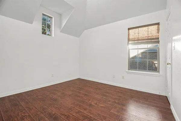 an empty room with wooden floor chandelier fan and windows