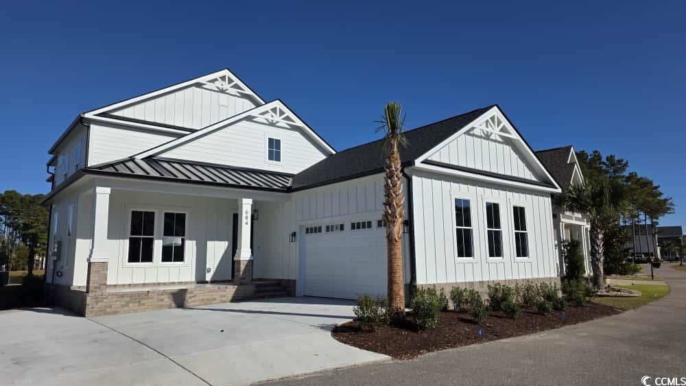 Modern farmhouse style home with board and batten siding, covered porch, and driveway