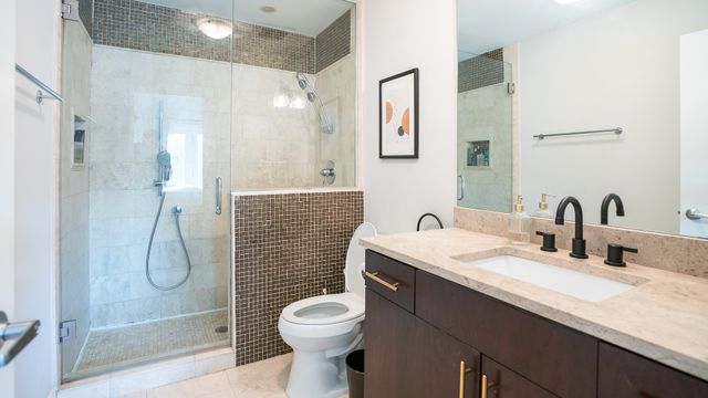 a bathroom with a granite countertop sink a toilet and shower