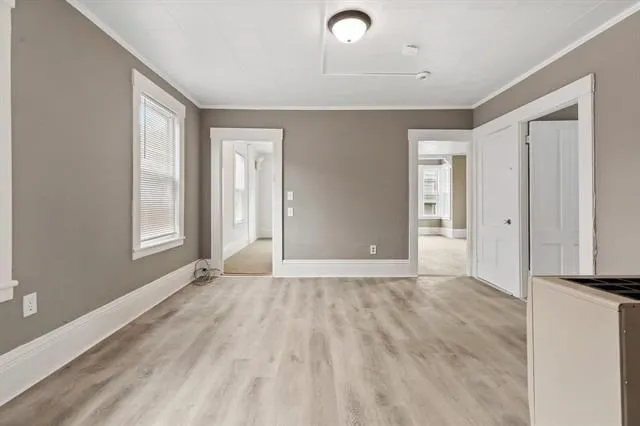 a view of an empty room with wooden floor and a window